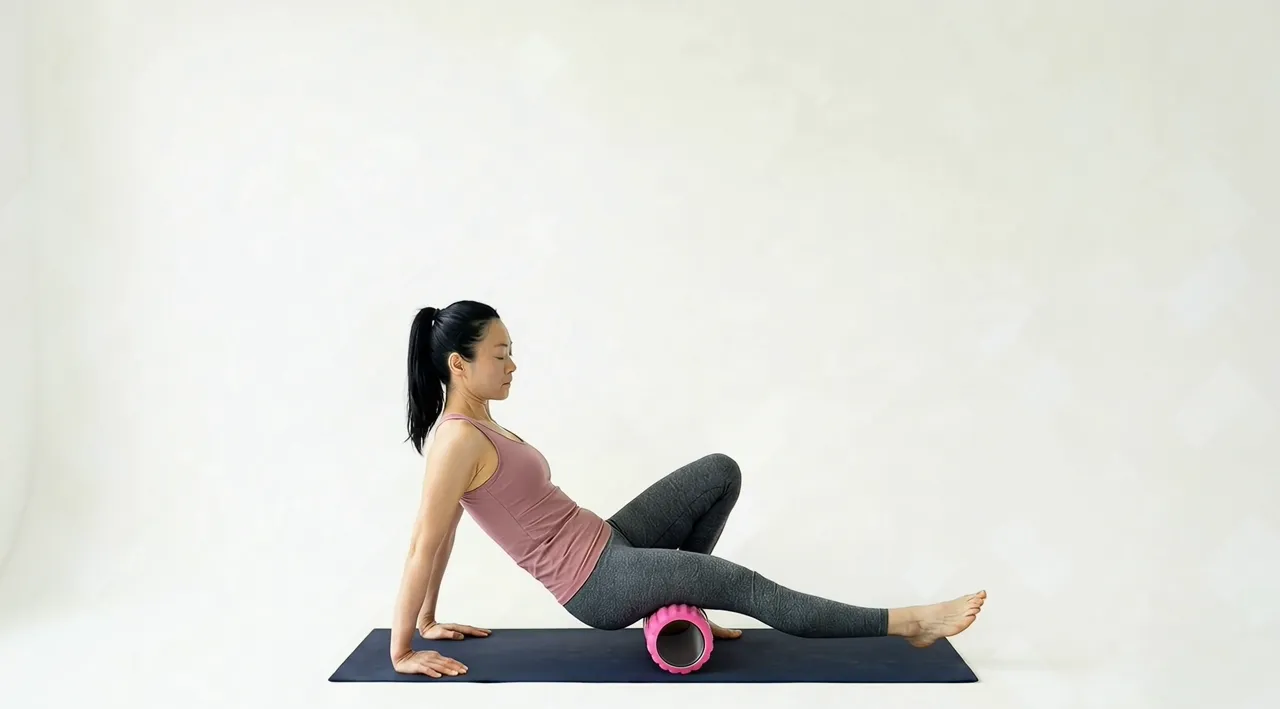 Looping video demonstration of the Hamstring Foam Roll exercise — a physician-designed movement performed on a mat in a bright studio.